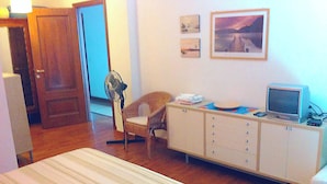 Ein Hotelzimmer mit einem Bett, einem Schreibtisch mit Computer, einem Sessel und einem Kleiderschrank.