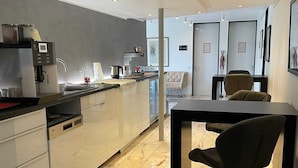 A modern kitchen with a central island, built-in appliances, and a dining area with a table and chairs. - SMC Münster - double room (Münster)