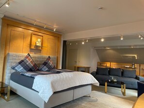 A modern bedroom with a large bed, a sofa, and a desk. - SMC Münster - double room (Münster)