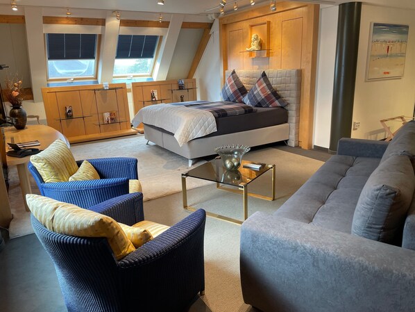 A modern living room with a bed, two sofas, a glass coffee table, and a dining area with a wooden table and chairs. - SMC Münster - double room (Münster)