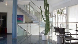 A modern interior with a glass staircase, a potted plant, and a seating area. - SMC Münster - double room (Münster)