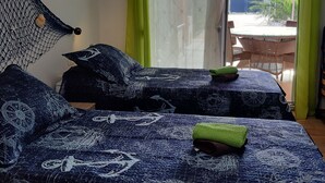 A room with a bed featuring a nautical-themed bedspread, a hammock, and a view of an outdoor area with a table and chairs. - Villa Mediteran Liznjan home with private pool in Istria
 (Ližnjan)