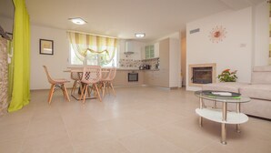 A modern living room with a dining area, a fireplace, and a kitchen in the background. - Villa Mediteran Liznjan home with private pool in Istria
 (Ližnjan)