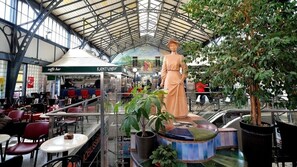 Amplio espacio interior con techo alto, que incluye una estatua, zonas de estar y una cafetería.