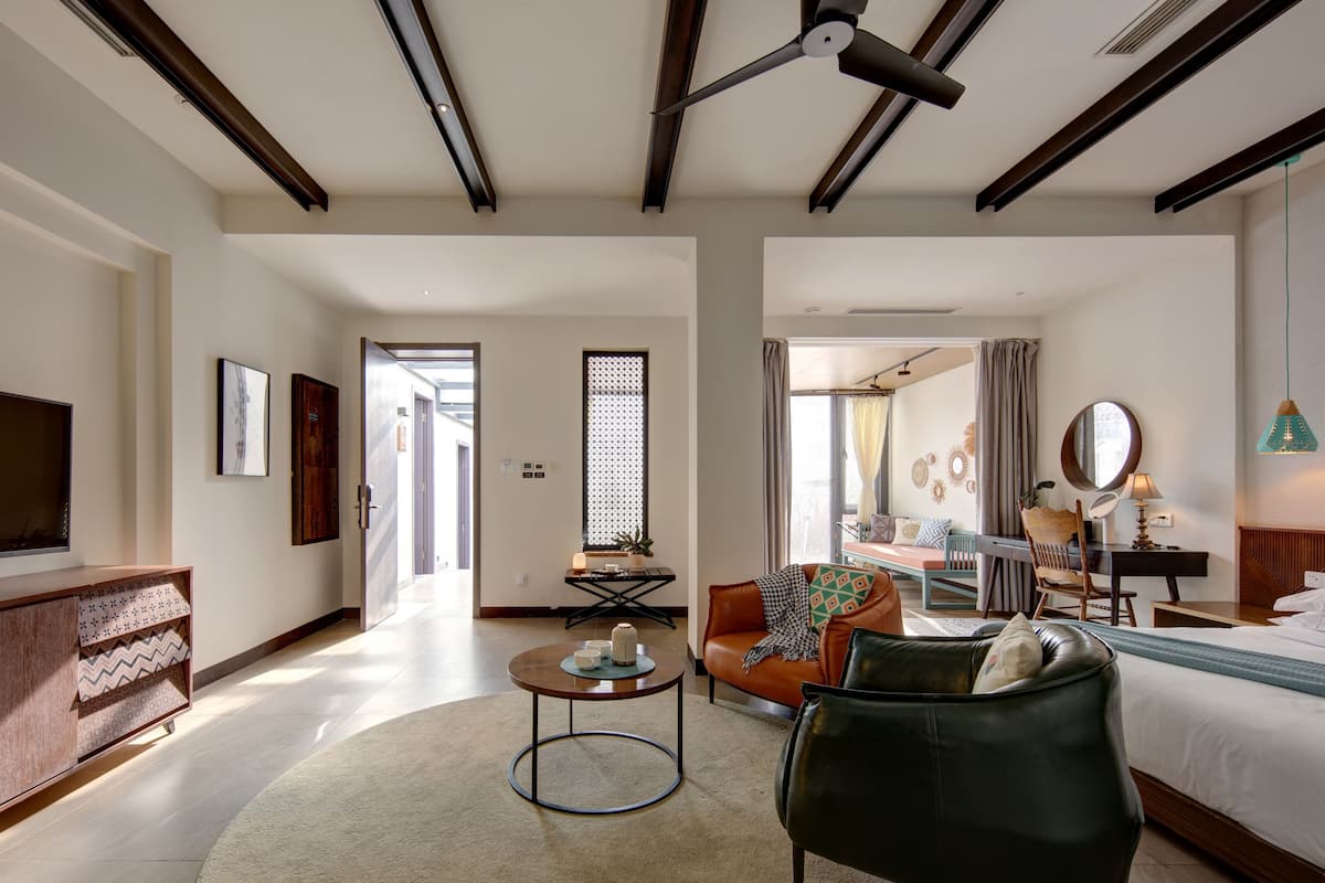 A spacious hotel room with a large bed, a sitting area with a coffee table, a television, and a ceiling fan.