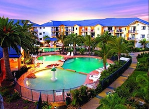 Un hôtel doté d’une grande piscine extérieure, de nombreux balcons et d’une végétation luxuriante.