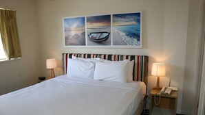 A hotel room with a large bed, two bedside tables with lamps, a telephone, and a wall with three framed pictures. - Gold Coast Family Apartment (Mermaid Beach)