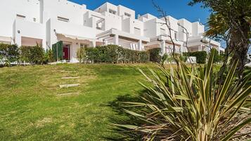 Un bâtiment moderne, de couleur blanche, avec une pelouse bien entretenue et une porte rouge.