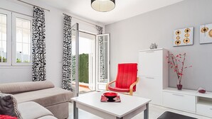 A modern living room with a sofa, a red chair, a white table, and a cabinet.