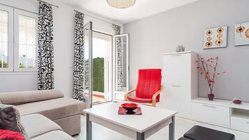 Un salon moderne avec un canapé, un fauteuil rouge, une table blanche et un meuble.