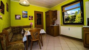 Un comedor con un banco de madera, una mesa con un florero y una ventana que ofrece vistas a la vegetación.