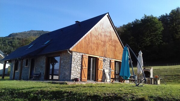 Un edificio rústico con fachada de piedra y exterior de madera, que presenta una gran puerta de madera y un paraguas azul.