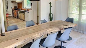 Un espace repas comprenant une longue table en bois, six chaises et deux lampes suspendues.
