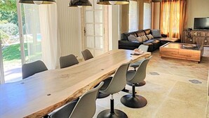 Un salon moderne avec une table à manger en bois, un canapé en cuir noir et un téléviseur posé sur un meuble en bois.