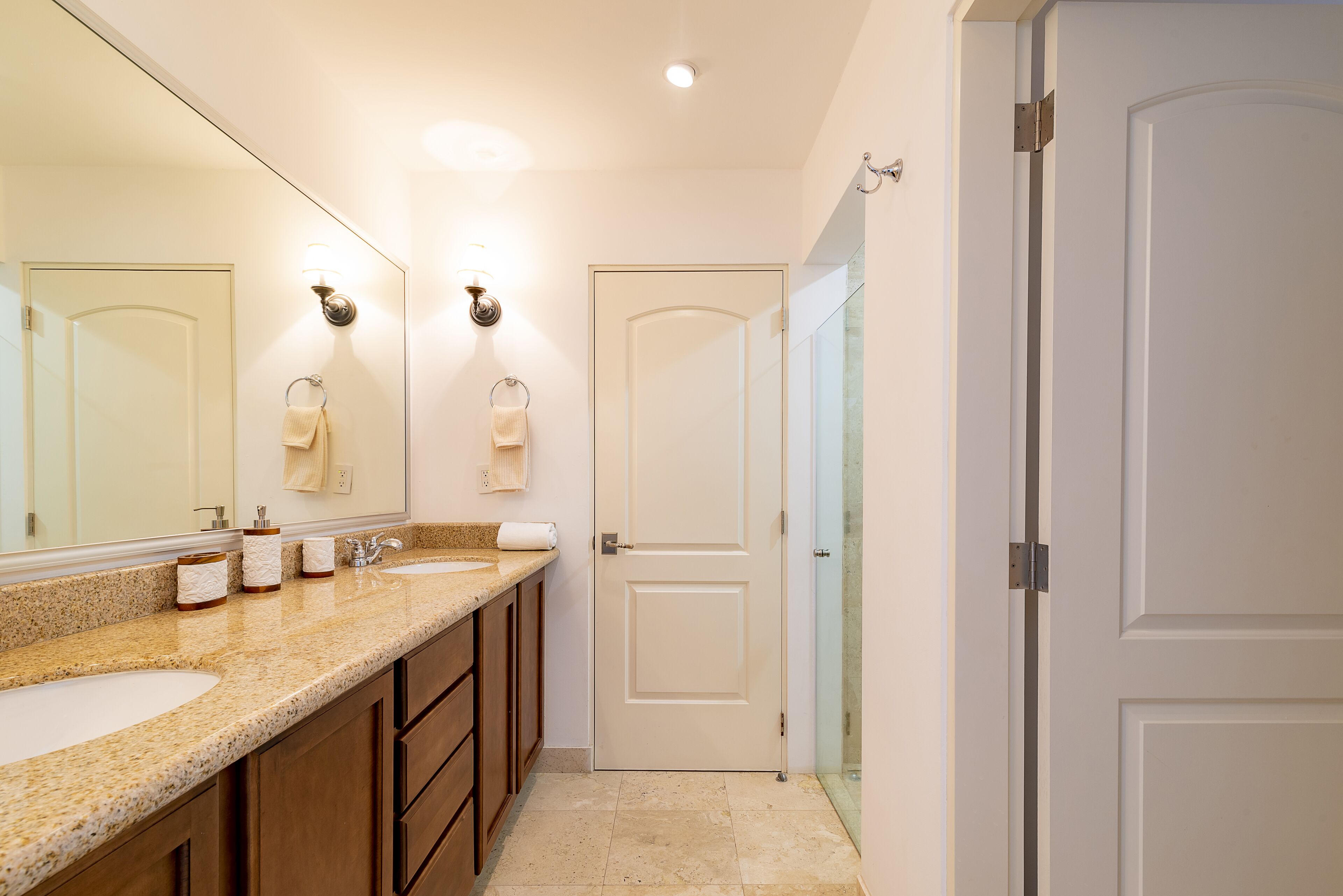 A bathroom with a double sink, a large mirror, and a glass shower enclosure.