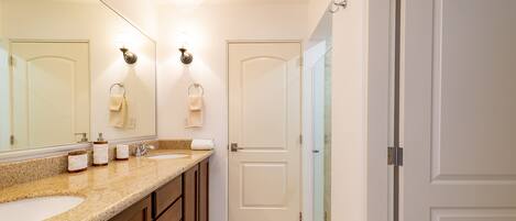 A bathroom with a double sink, a large mirror, and a glass shower enclosure.