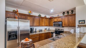 A modern kitchen with granite countertops, stainless steel appliances, wooden cabinets, and decorative items on the upper cabinets. - Memorable revival unit (La Paz)
