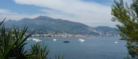A coastal city with boats on the water and mountains in the background.