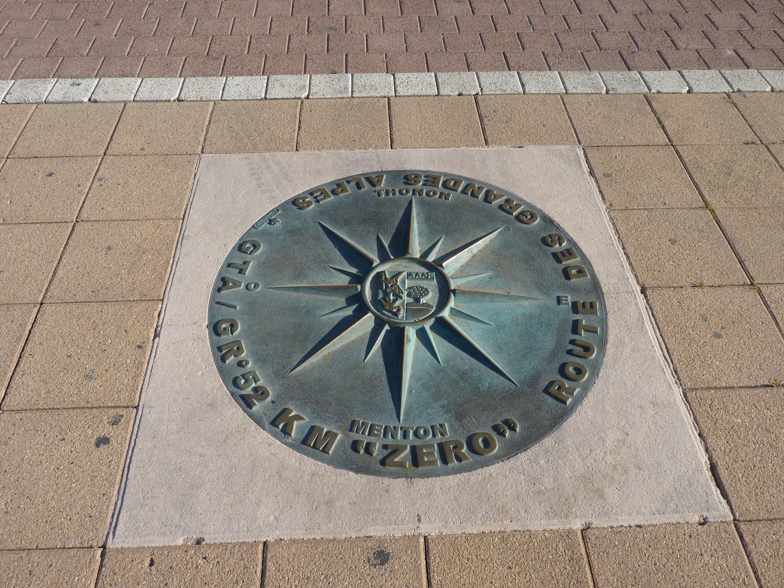A metal plate with a compass design and text indicating a location.
