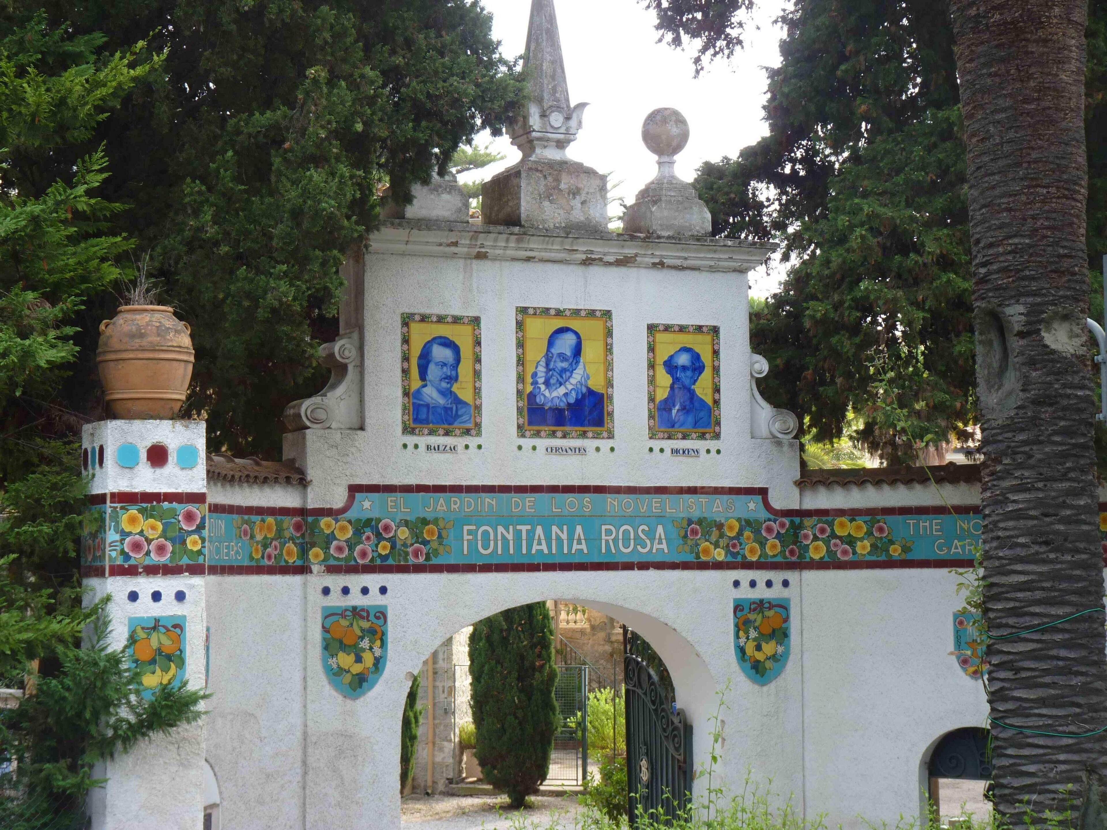 Un arco de azulejos con retratos y el nombre 'Fontana Rosa' en un sendero de jardín.