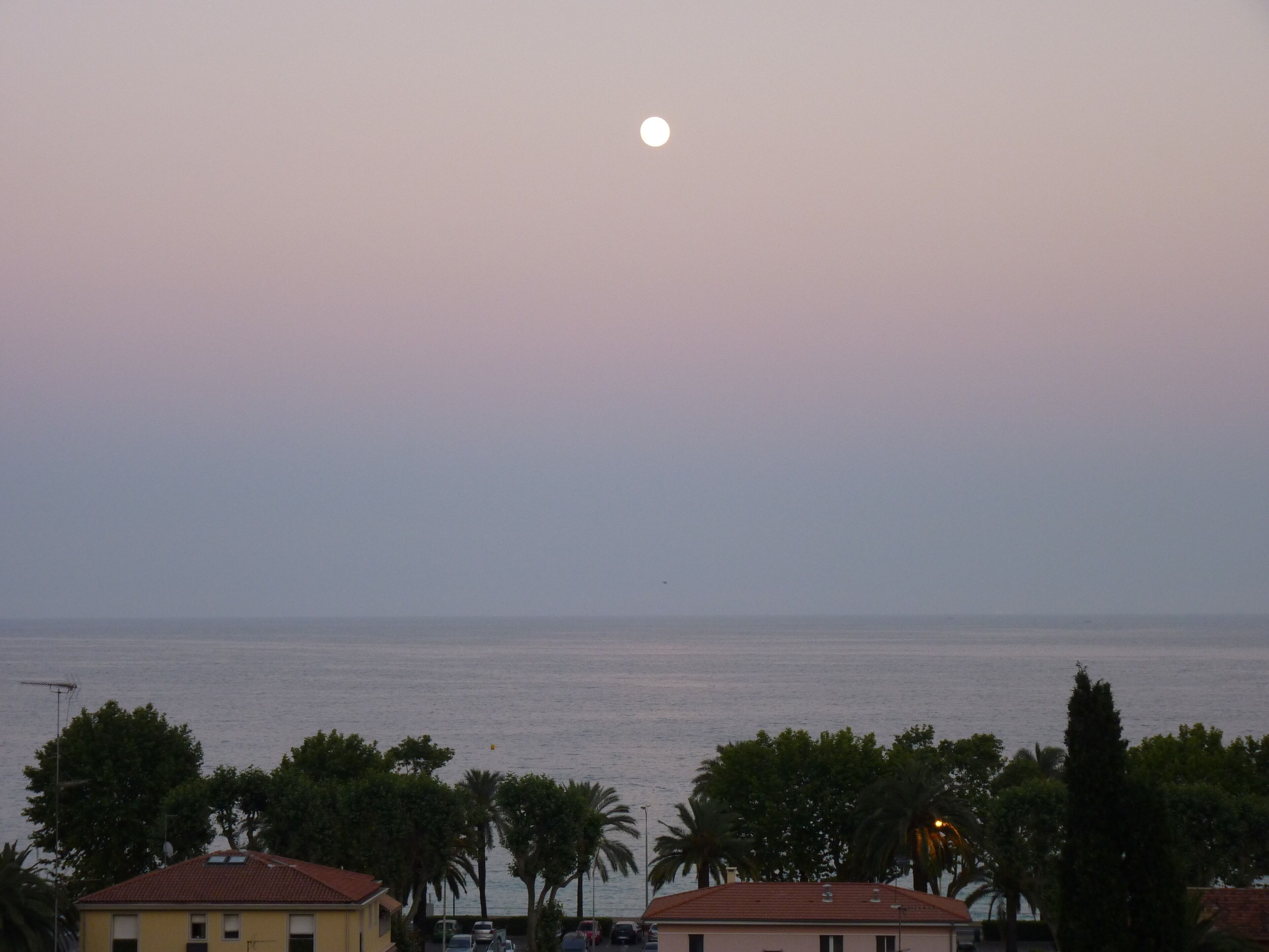 A coastal view with a building in the foreground and a calm sea.
