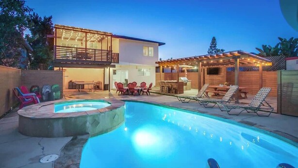 Ett modernt hus med en swimmingpool, utomhusmöbler och en täckt uteplats.