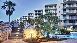 Un hotel con varios balcones, piscina y una escalera que lleva a la entrada.