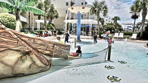 Parque acuático con piscina de olas, palmeras y un edificio al fondo.