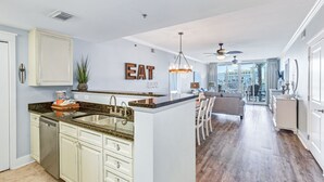 Una cocina moderna con una isla central, un comedor con vistas y un salón con ventilador de techo.