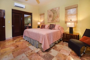 A bedroom with a bed, a nightstand, a chair, and a wall-mounted lamp.