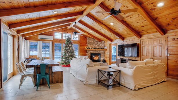 Un intérieur de chalet chaleureux avec une cheminée en pierre, un grand téléviseur et un sapin de Noël.