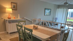 A dining area with a table and chairs, a lamp, a picture frame, and a view of the outside.