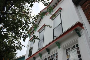 Un edificio con fachada blanca, marcos de ventanas verdes y un letrero que indica alquileres vacacionales.