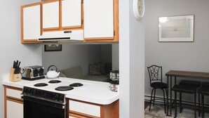Une cuisine compacte avec des meubles blancs, une cuisinière et un petit coin repas comprenant une table et des chaises.