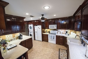 A kitchen with dark wooden cabinets, a microwave, a stove, and a washing machine. - Pine Island Paradise on Caddo with Generator (Karnack)