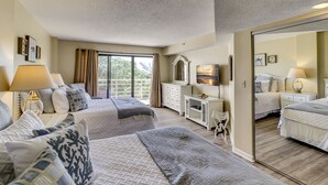 Habitación de hotel con dos camas, un espejo grande, un televisor y un gran ventanal corredizo al balcón.