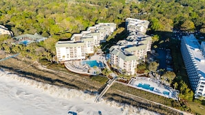 Vista aérea de un complejo turístico con varias construcciones, una piscina y una zona de playa.