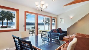 A dining area with a large table and chairs, a chandelier, and a view of a lake through large windows.