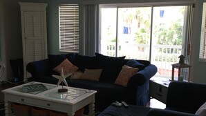 A living room with a ceiling fan, a sofa, a coffee table, and a view through a sliding glass door.