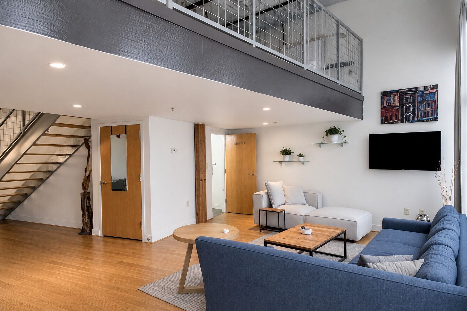 Una sala moderna con una escalera, un televisor de pantalla plana y un sofá.