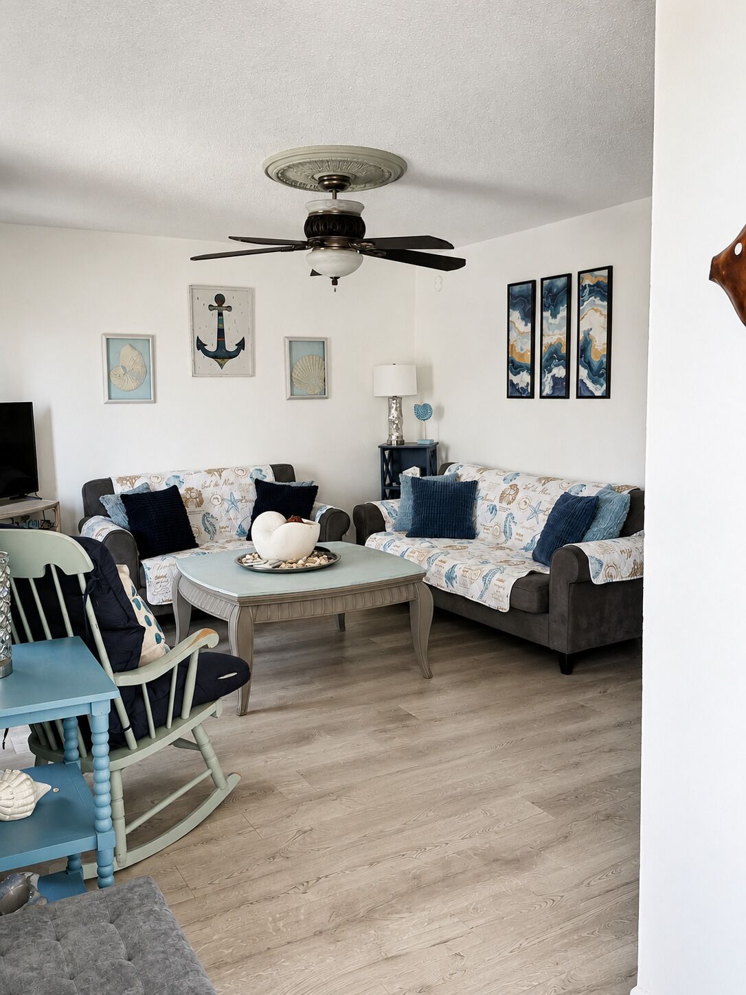 A living room with a ceiling fan, two sofas, a coffee table, a rocking chair, and a television.