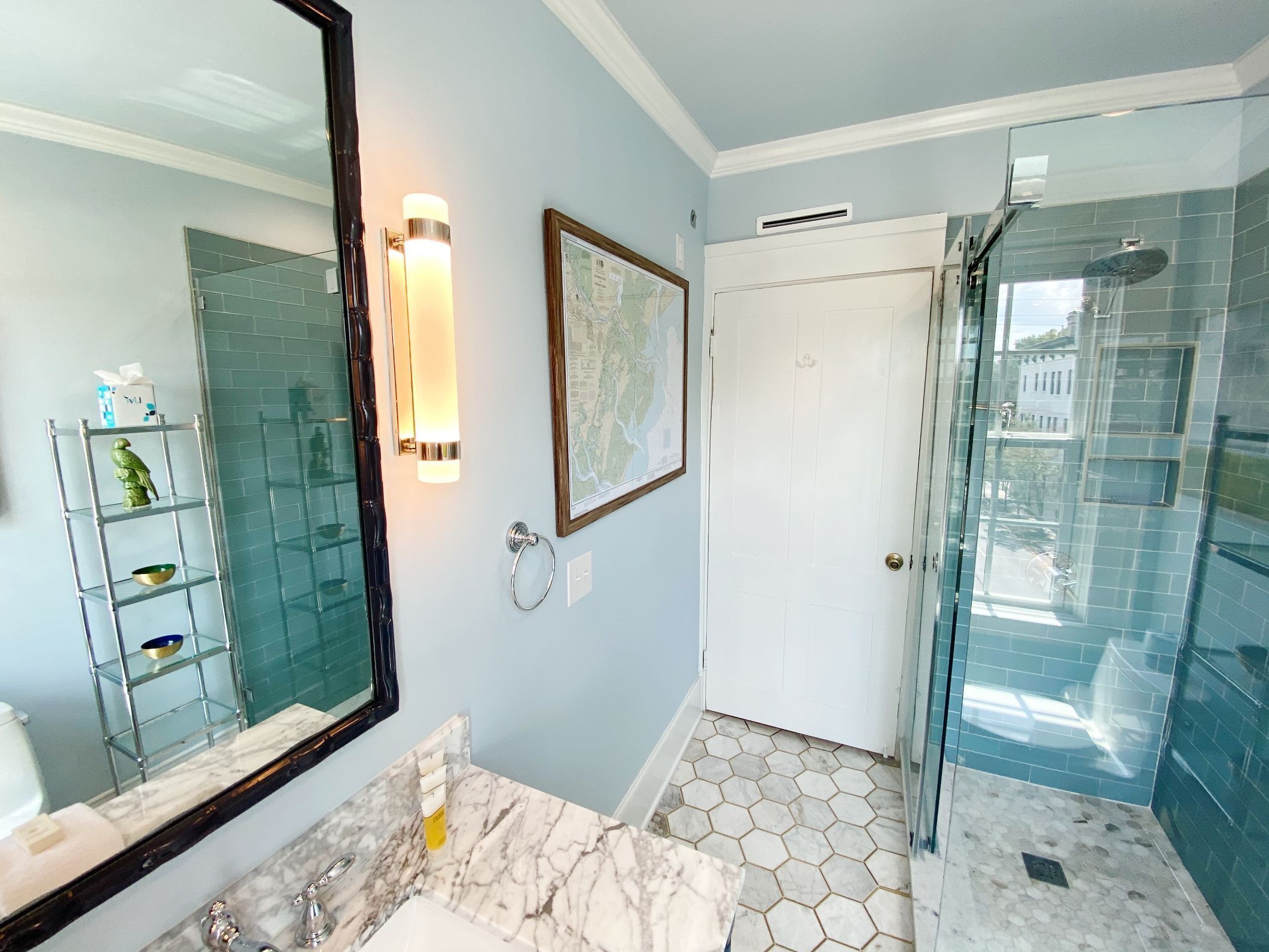 A bathroom with a large mirror, a marble countertop, a glass shower enclosure, and a map on the wall.