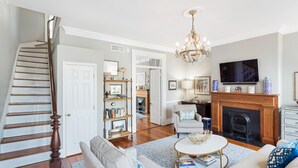 Ein Wohnzimmer mit Treppe, Kamin, Fernseher und einer Chandelier.