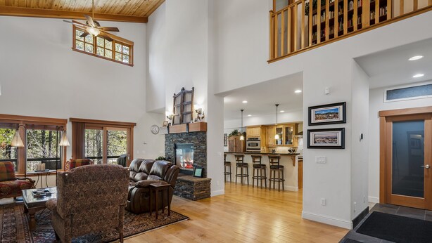 A spacious living room with a fireplace, a dining area with bar stools, and a kitchen with wooden cabinets.