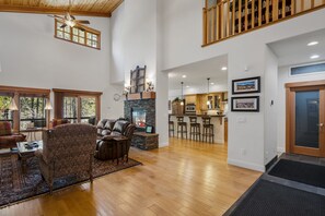 A spacious living room with a fireplace, a dining area with bar stools, and a kitchen with wooden cabinets.