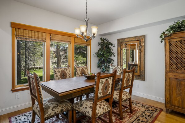 A dining room with a wooden table, matching chairs, and a chandelier.