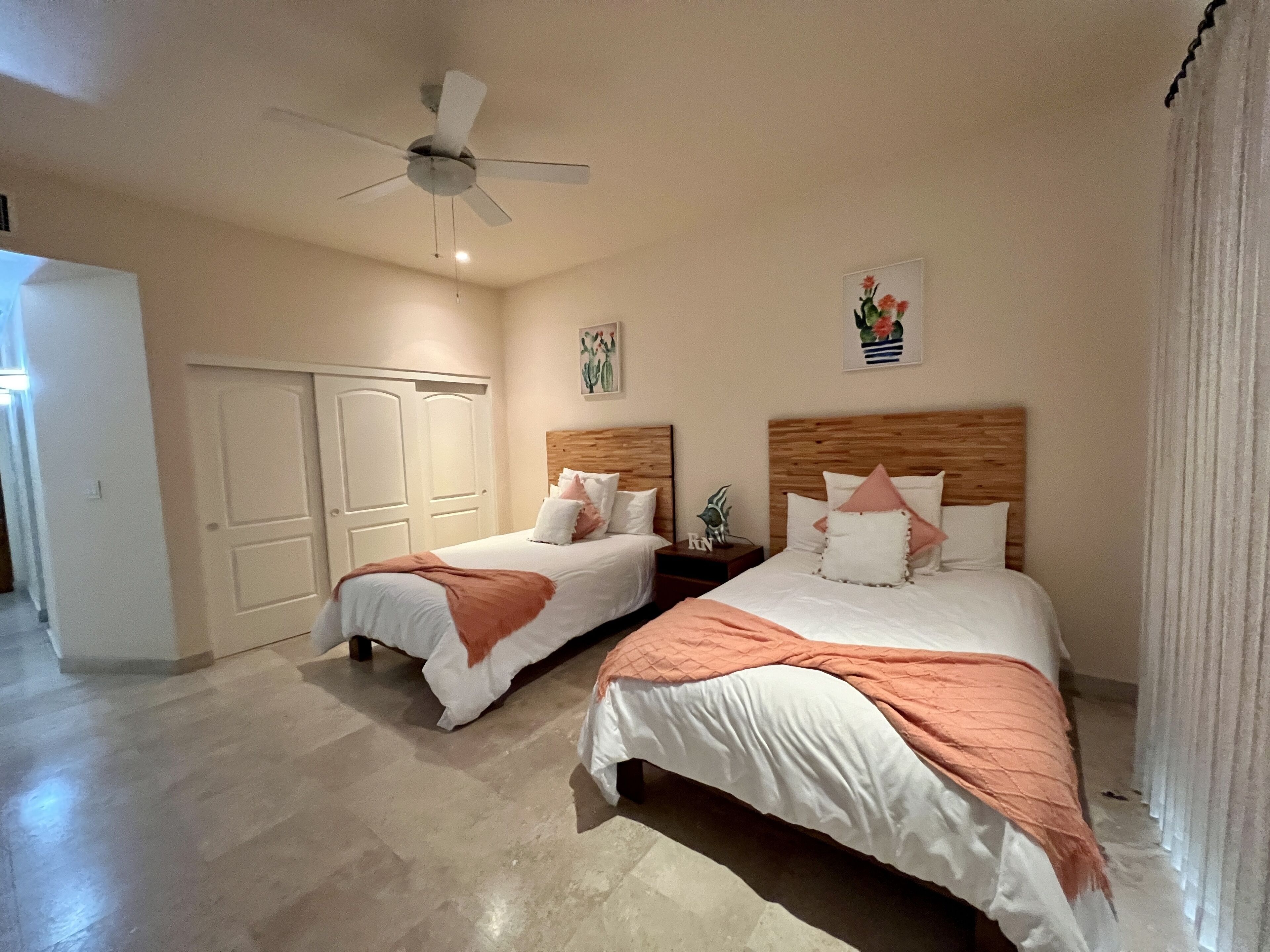 Een hotelkamer met twee bedden, een plafondventilator en een deur.