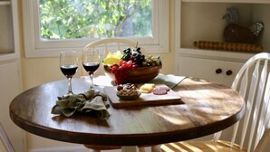 A wooden table with a bowl of grapes, cheese, and a cutting board with sliced meats. Two glasses of red wine are on the table.