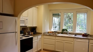 A kitchen with white cabinets, a stove, a microwave, and a sink.