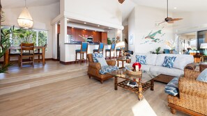 A spacious living area with a sofa, chairs, a coffee table, and a kitchen in the background. - NOV '26 Available! - INCREDIBLE 220 DEGREE OCEAN VIEW VILLA, SPA & FOUNTAIN POOL (Kamuela)